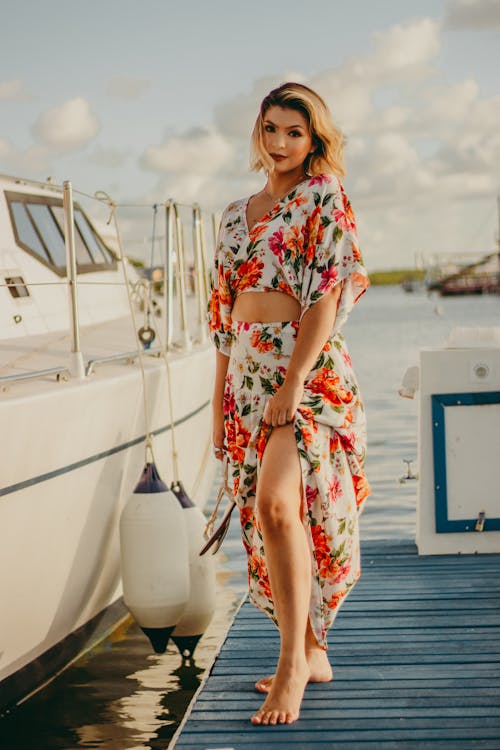 Free Woman in a Floral Dress Posing Near a Boat Stock Photo