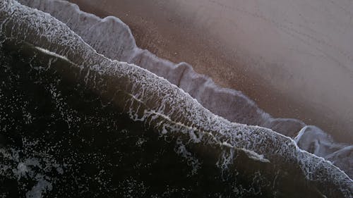 Aerial View of Ocean Waves Kissing the Beach Shore