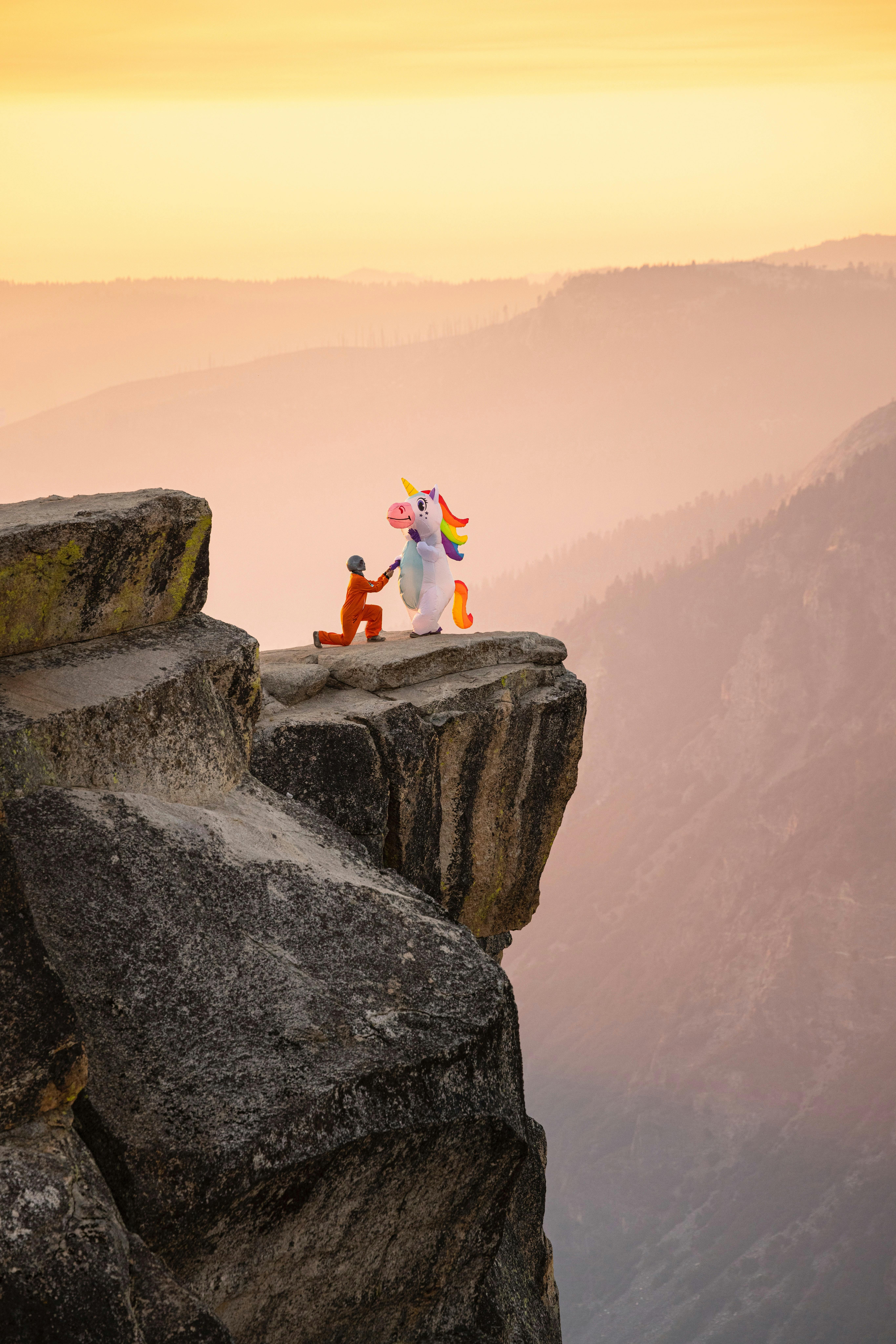 A surreal scene with a person and unicorn on a rocky cliff at sunset.