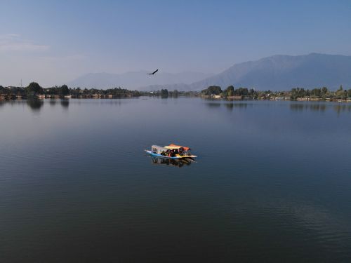 Free Peaceful scene of a houseboat on Nigeen Lake with a mountain backdrop. Stock Photo