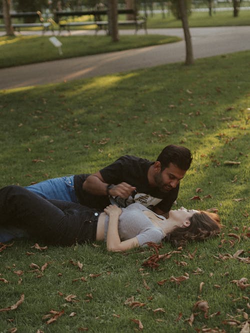 Free A Couple Lying on the Grass at a Park Stock Photo