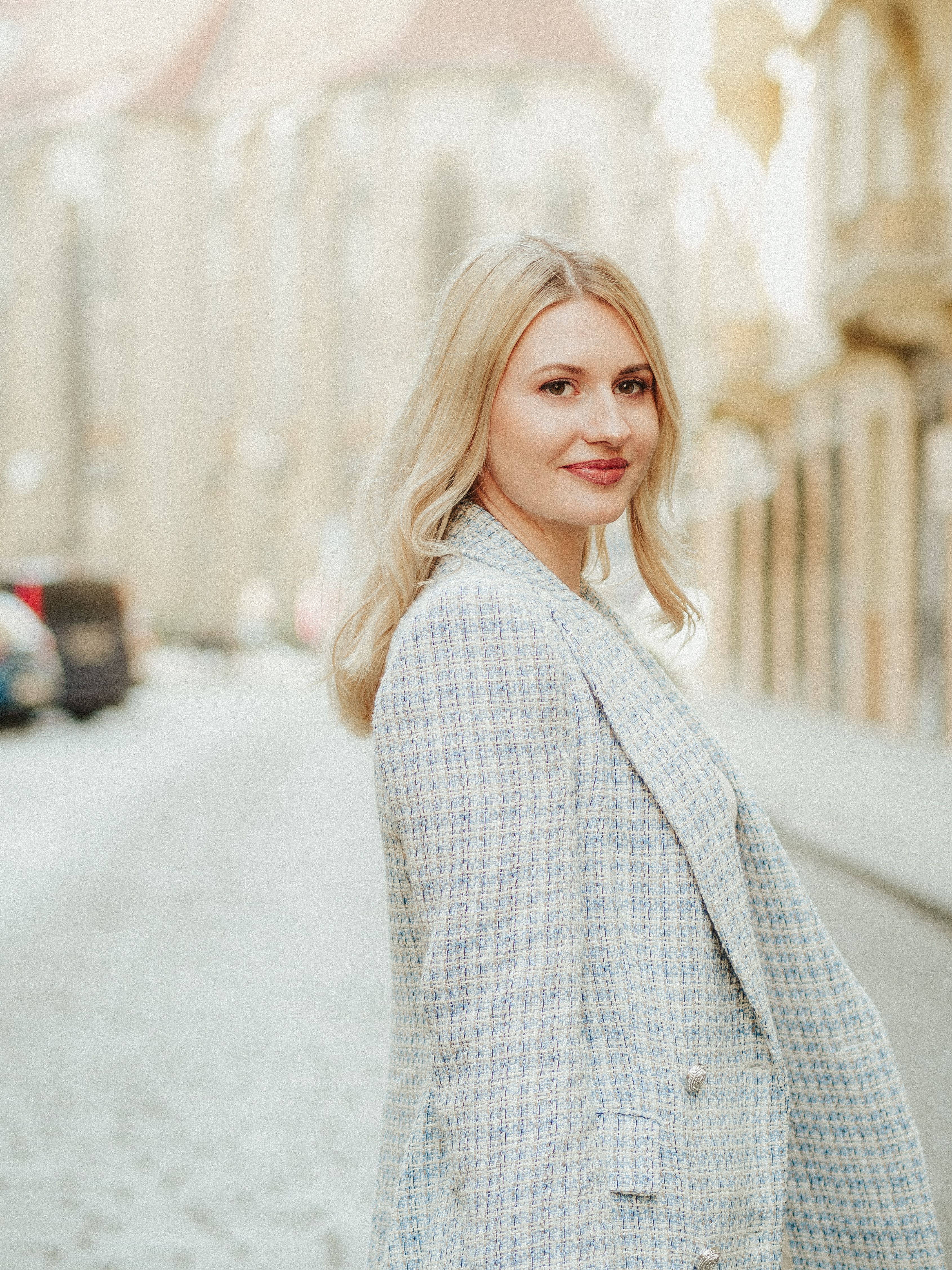 Fashionable woman with blond hair smiling on an old town street. Portrait shot.