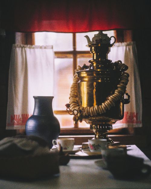 Free Elegant vintage samovar with tea set and decor on a table by the window, in a cozy indoor setting. Stock Photo
