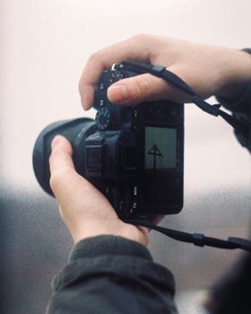 Close-up of hands holding a camera outdoors, capturing a scene on the display screen.
