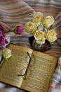 Glasses Laying on Open Book with Pink and Creamy Roses Around