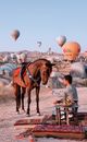 Man Feeding Horse with Balloons in Background