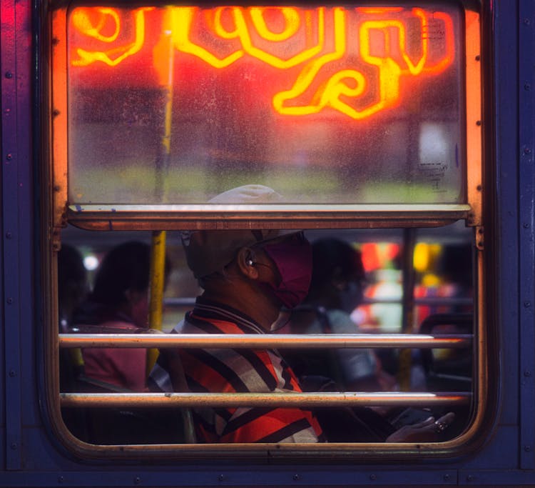 A Profile View Of A Man In A Bus Waring A Face Mask 