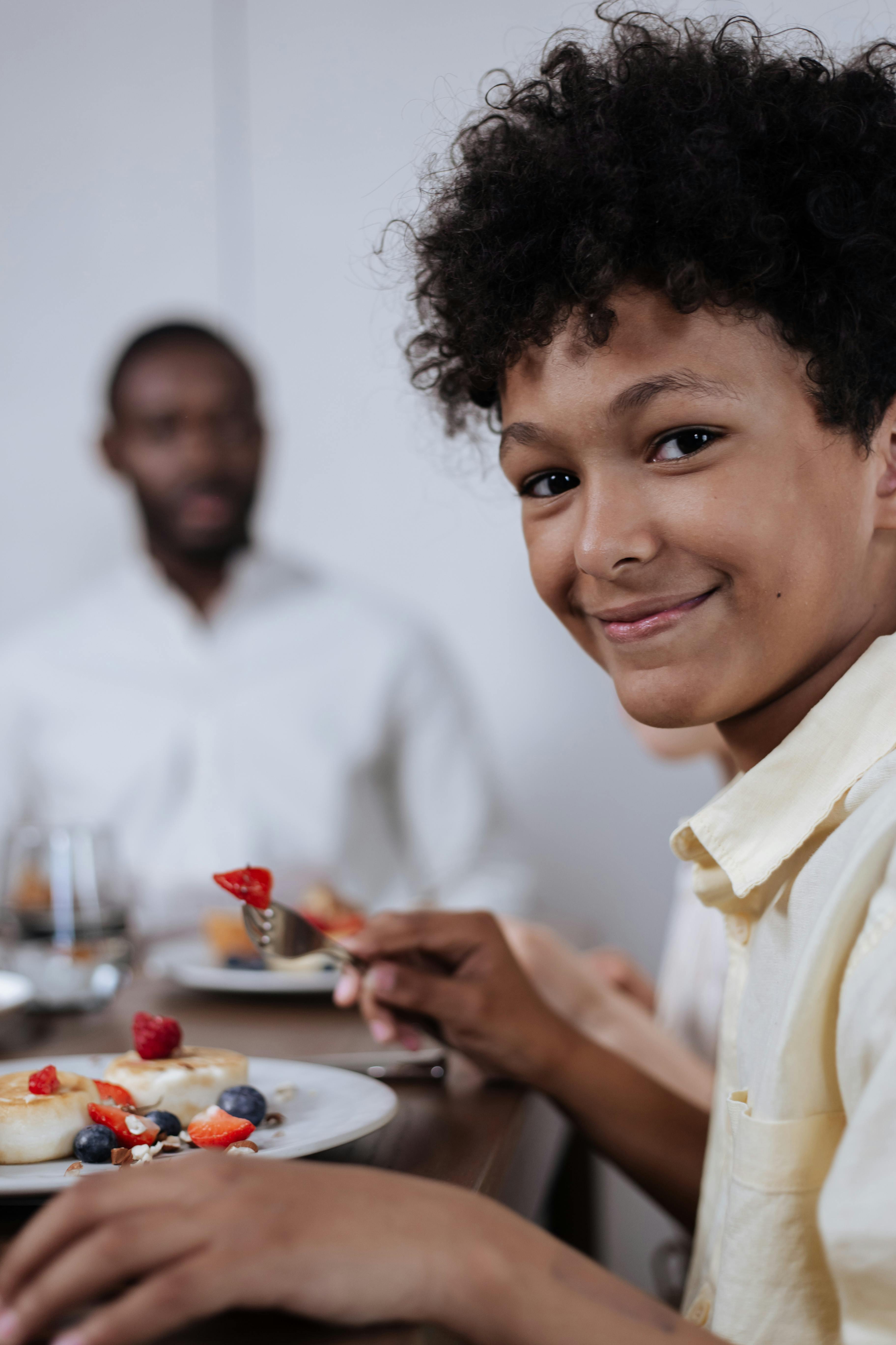 boy smiling at camera with his father in background