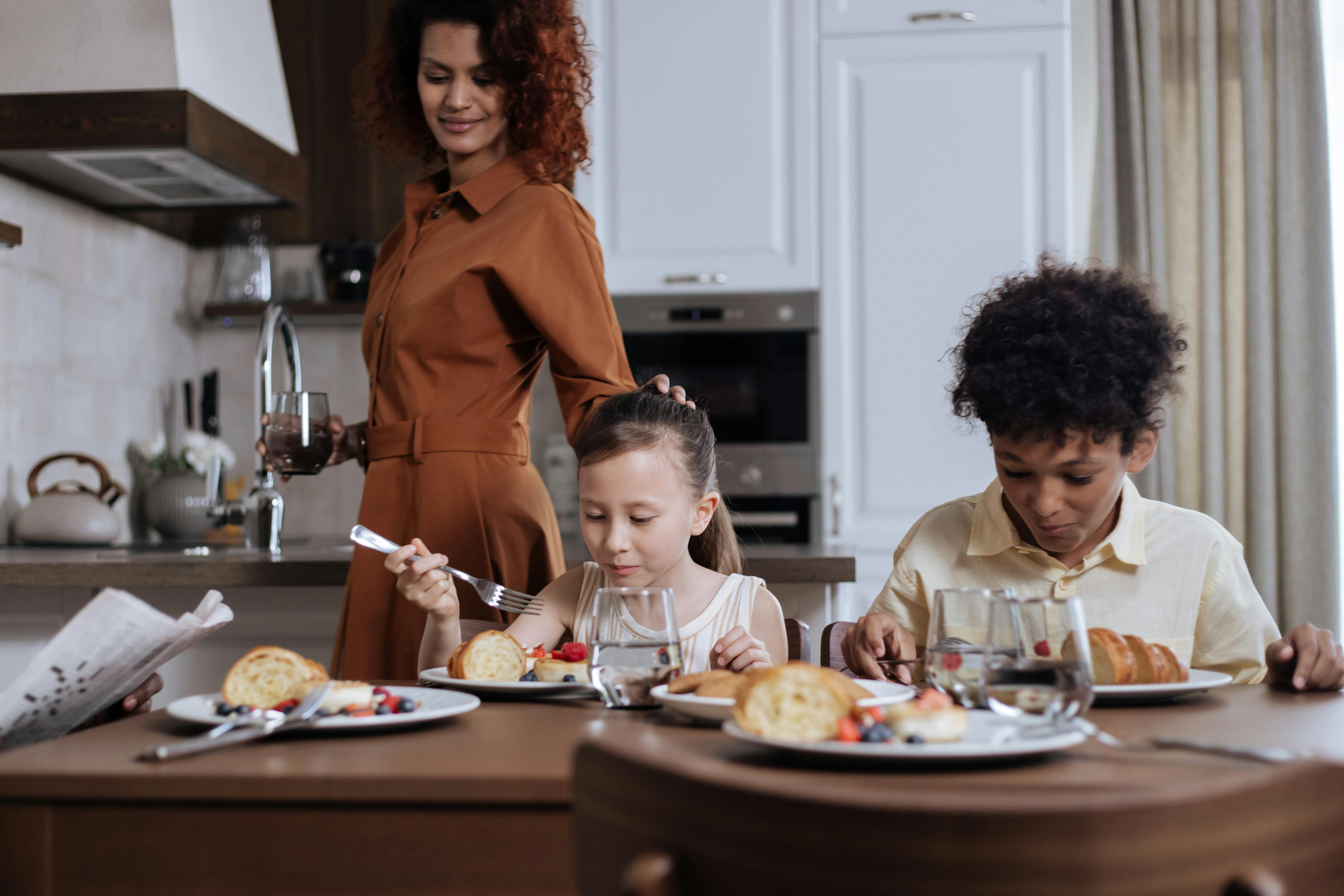 mom looking at children eating breakfast