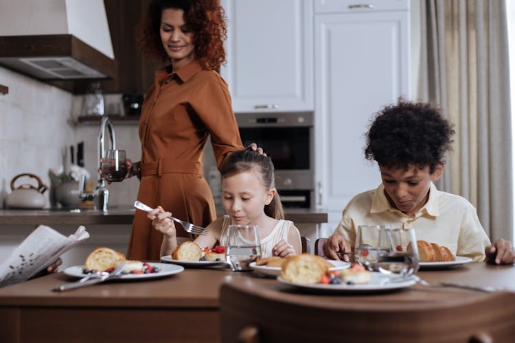 Mom Looking At Children Eating Breakfast 