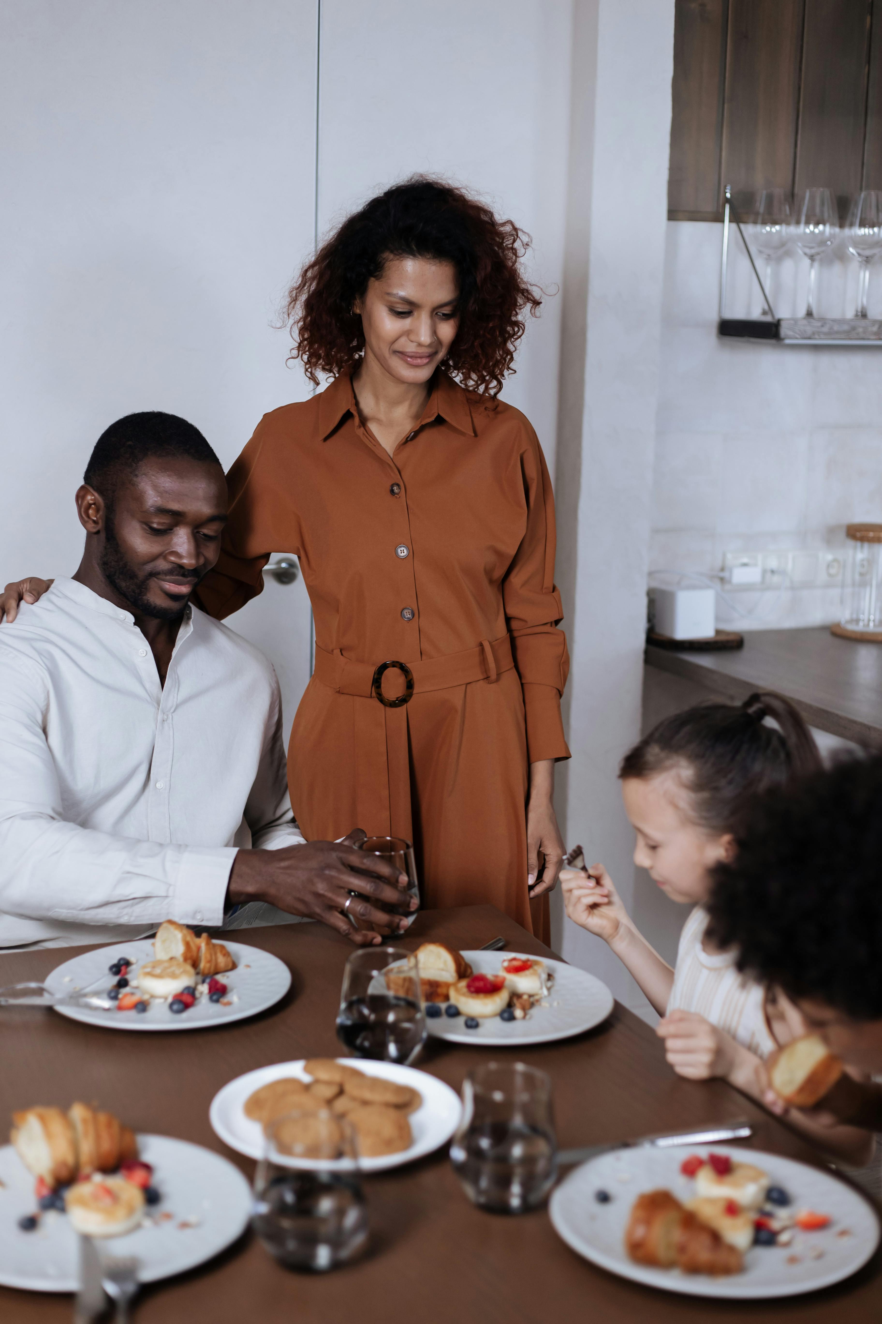 A family gathered indoors enjoying a breakfast with fruits and pastries.