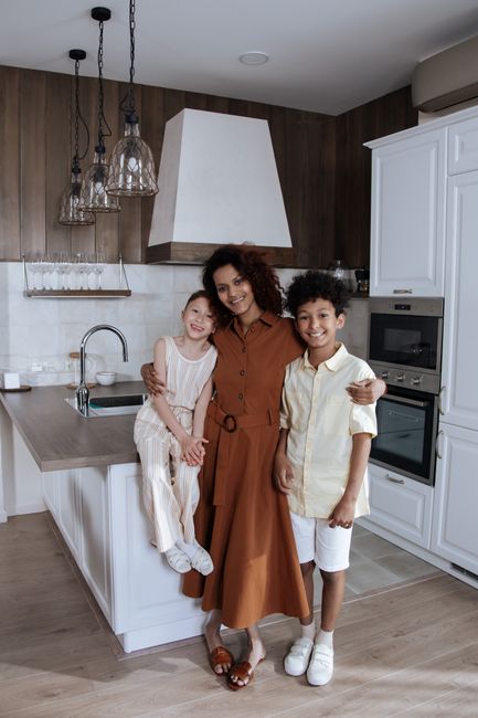 Photo by Ron Lach on Pexels A joyful family moment in a stylish kitchen with a mother and her two children posing together.