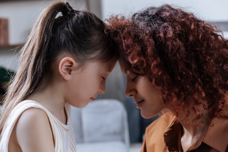 Mother And Daughter Touching With Heads