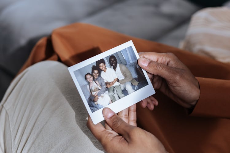 Close Up In Mans Hands Holding Family Photograph