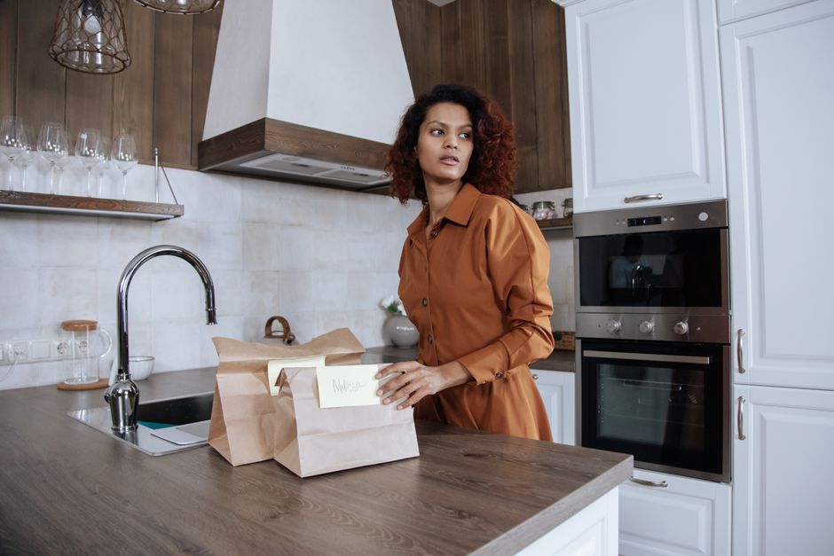 Photo by Ron Lach on Pexels Woman packing lunch bags in a stylish kitchen, looking thoughtful.