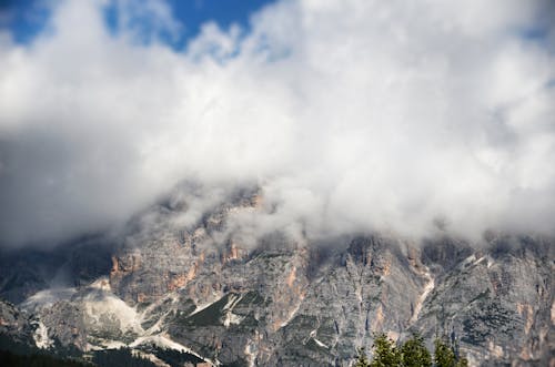 Rocky Mountain Covered with White Clouds Under Blue Sky