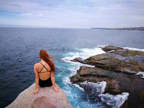 Free Woman Wearing Monokini on Rock Clip Near Body of Water Stock Photo