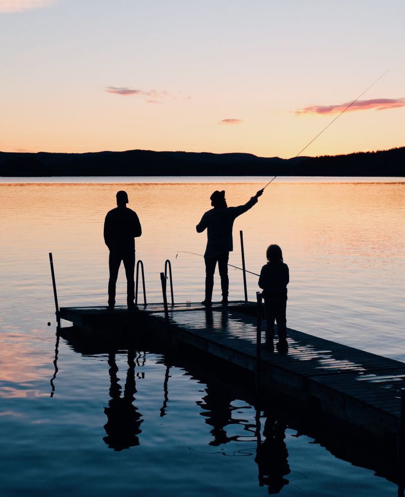 A family fishing from a dock at sunset