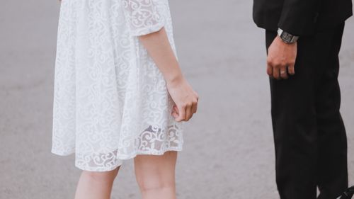 Free Close-up of a couple standing together outdoors in white dress and black suit. Stock Photo