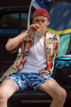 Casual young man relaxing with a soda in hand, enjoying the sunny day outdoors.