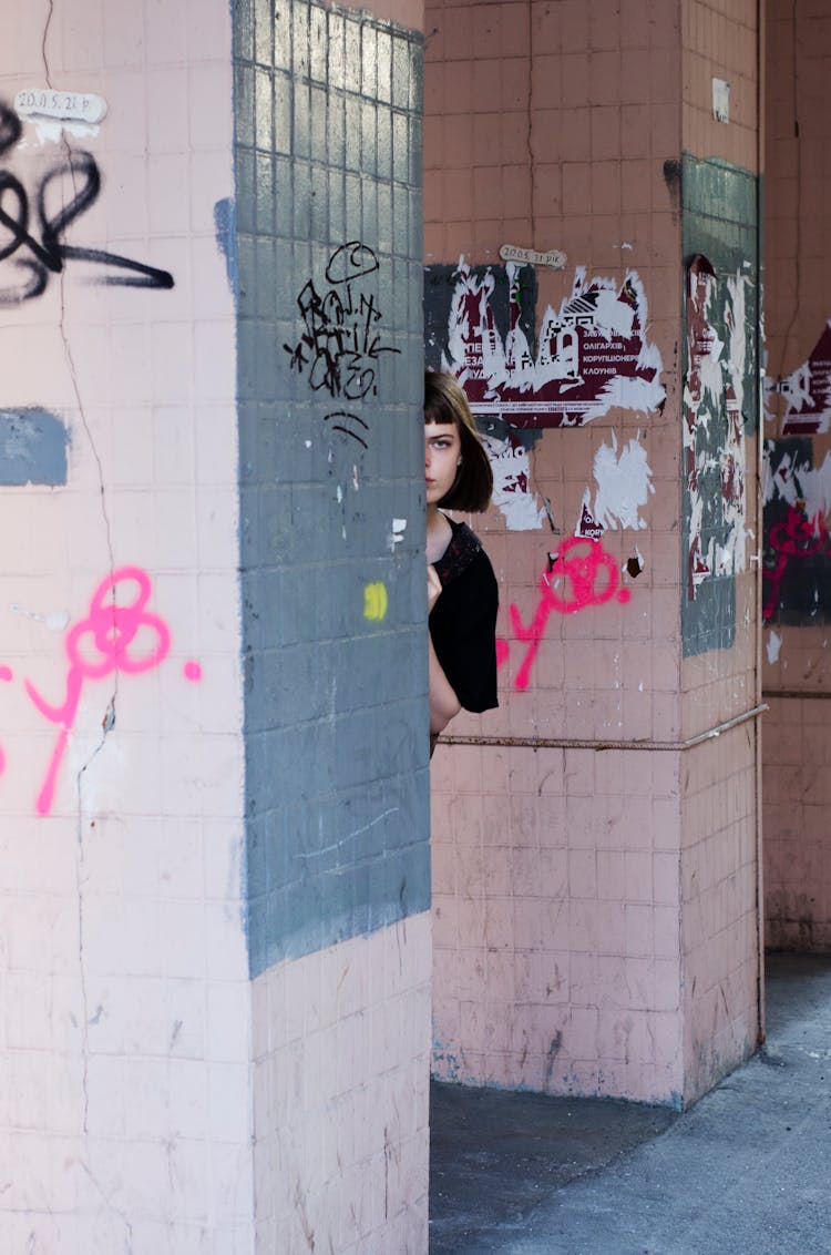 Young Woman Peeking Behind A Wall 