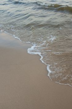 Gentle waves washing onto a pristine sandy beach, capturing a serene seaside moment.