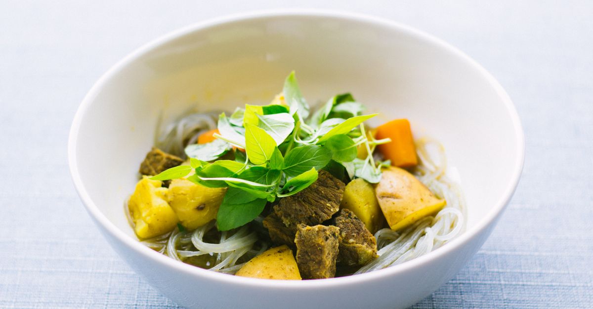 A savory bowl of Vietnamese noodle soup garnished with fresh herbs and vegetables