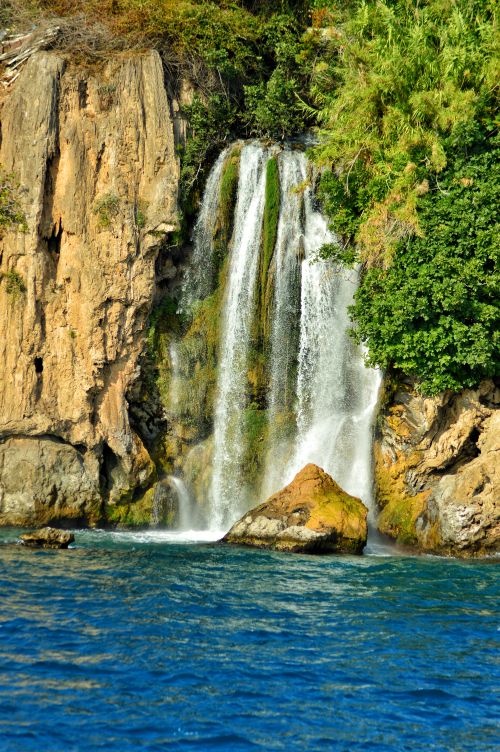 Free Breathtaking waterfall cascading into a vibrant blue lagoon surrounded by lush vegetation. Stock Photo