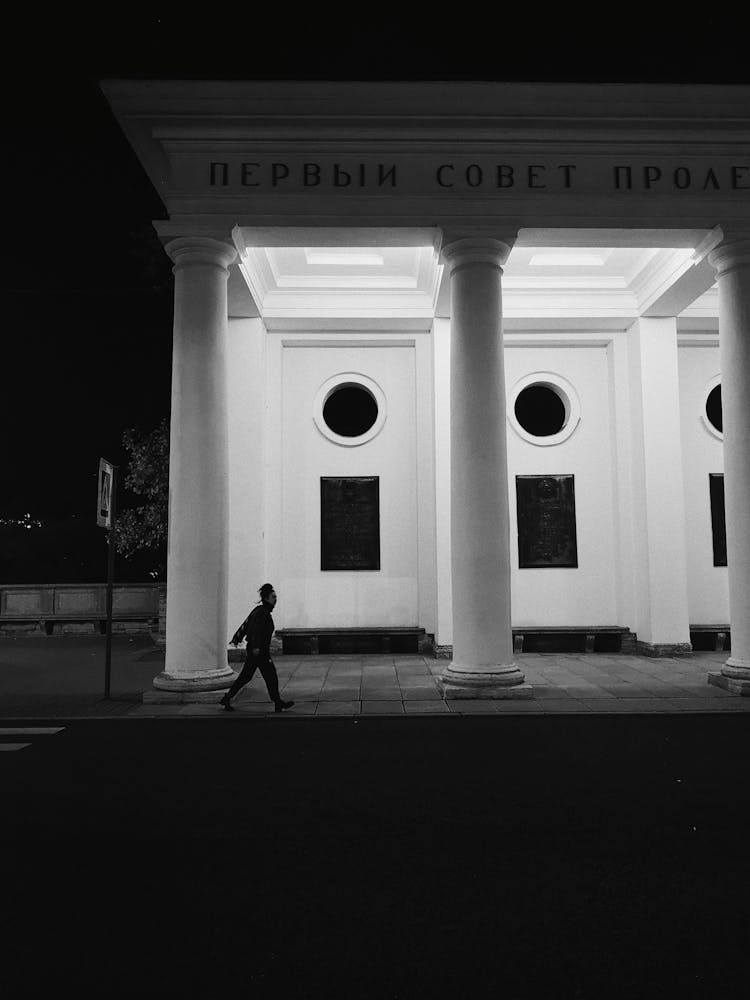 Person Passing By A Building At Night