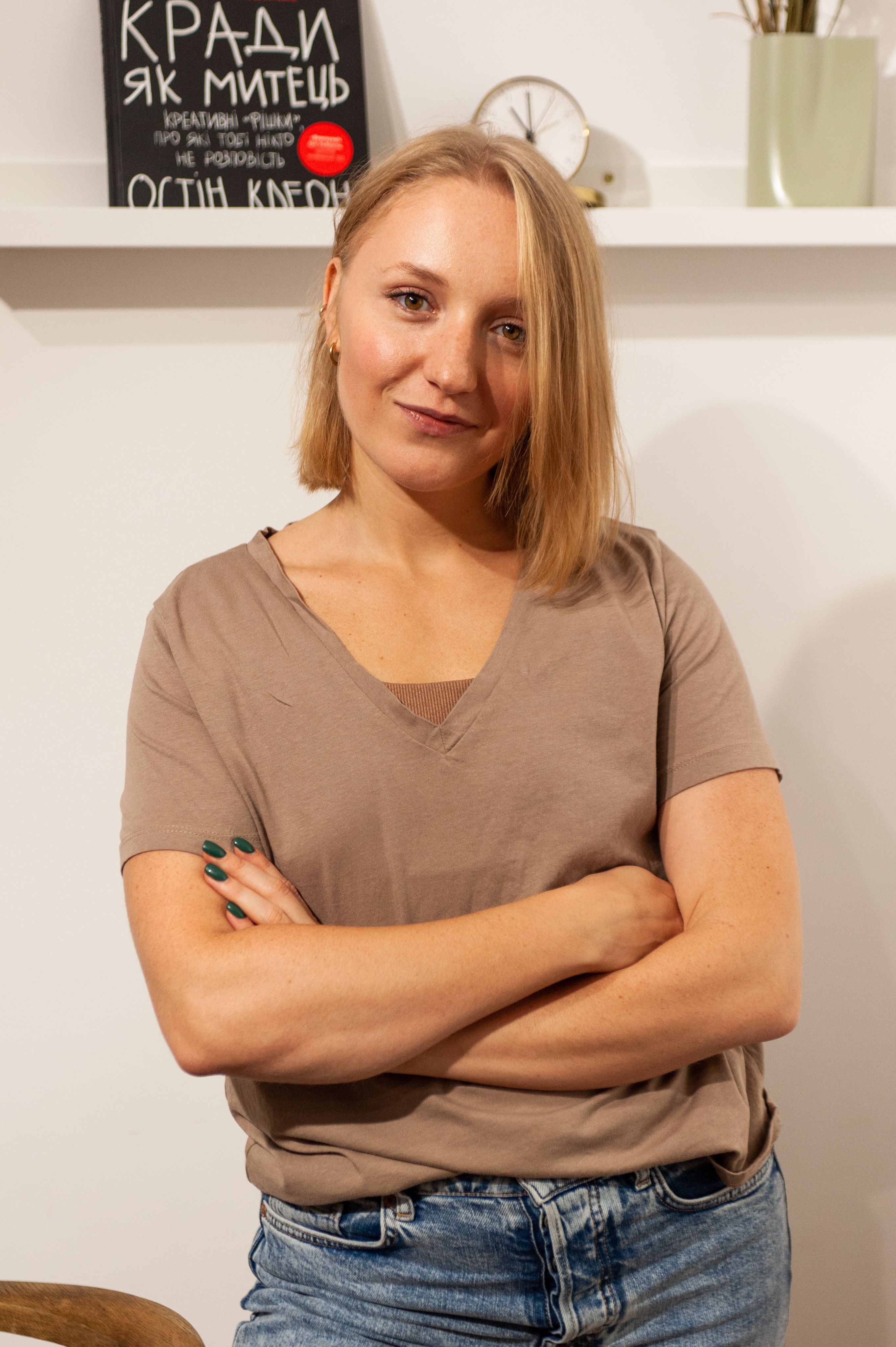 Relaxed young woman with arms crossed, smiling in a home setting.