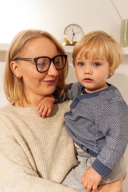 Free A woman with glasses lovingly holding her toddler indoors. Stock Photo