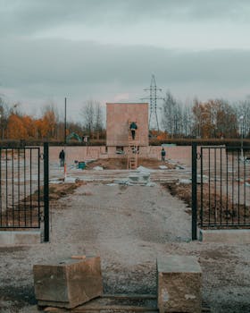 Workers constructing a stone structure at an outdoor site during the fall season.