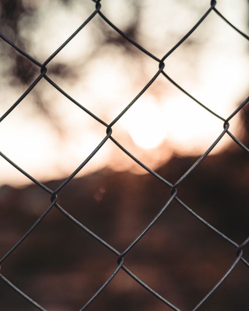 Free Close-up of a metal chain fence with a sunset backdrop in Barcelona. Stock Photo