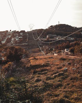 Peaceful hillside in Barcelona with cable cars and rustic landscape at sunset.