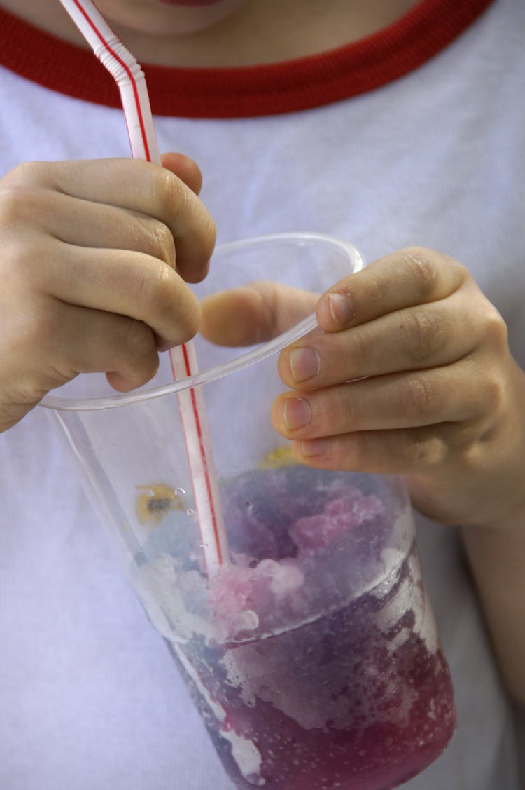 Person Holding Clear Plastic Cup With A Straw