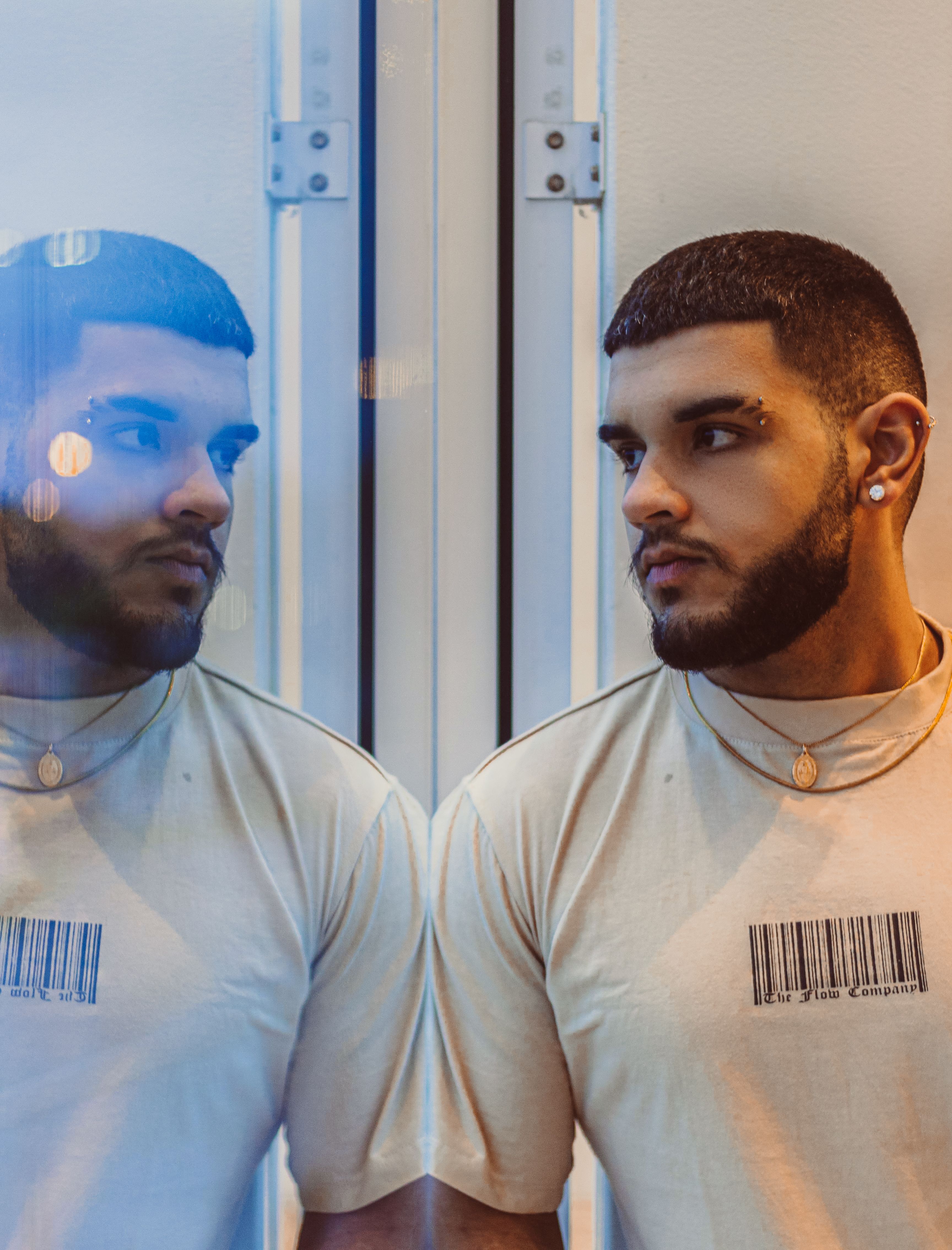 Portrait of a stylish bearded man reflecting in a mirror wearing a barcode shirt.