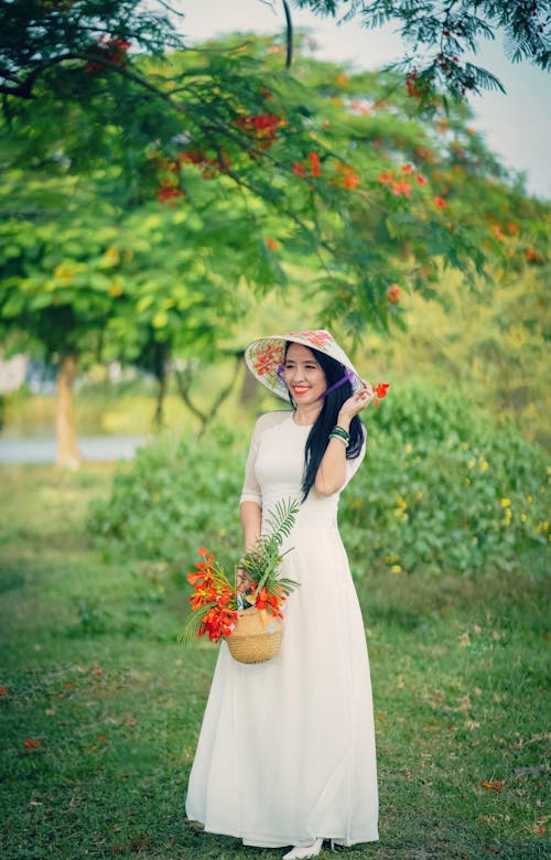 Kostenloses Stock Foto zu asiatische frau, blumen, chapéu cònic asiàtic