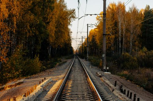 Free A serene railway track cutting through a forest with vibrant autumn foliage, perfect for travel and nature themes. Stock Photo