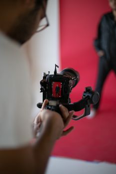 Professional photographer capturing model with Canon EOS 6D in studio setting with red backdrop.