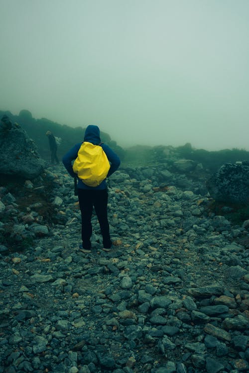 Person in Blue Hoodie Standing on Rocky Ground