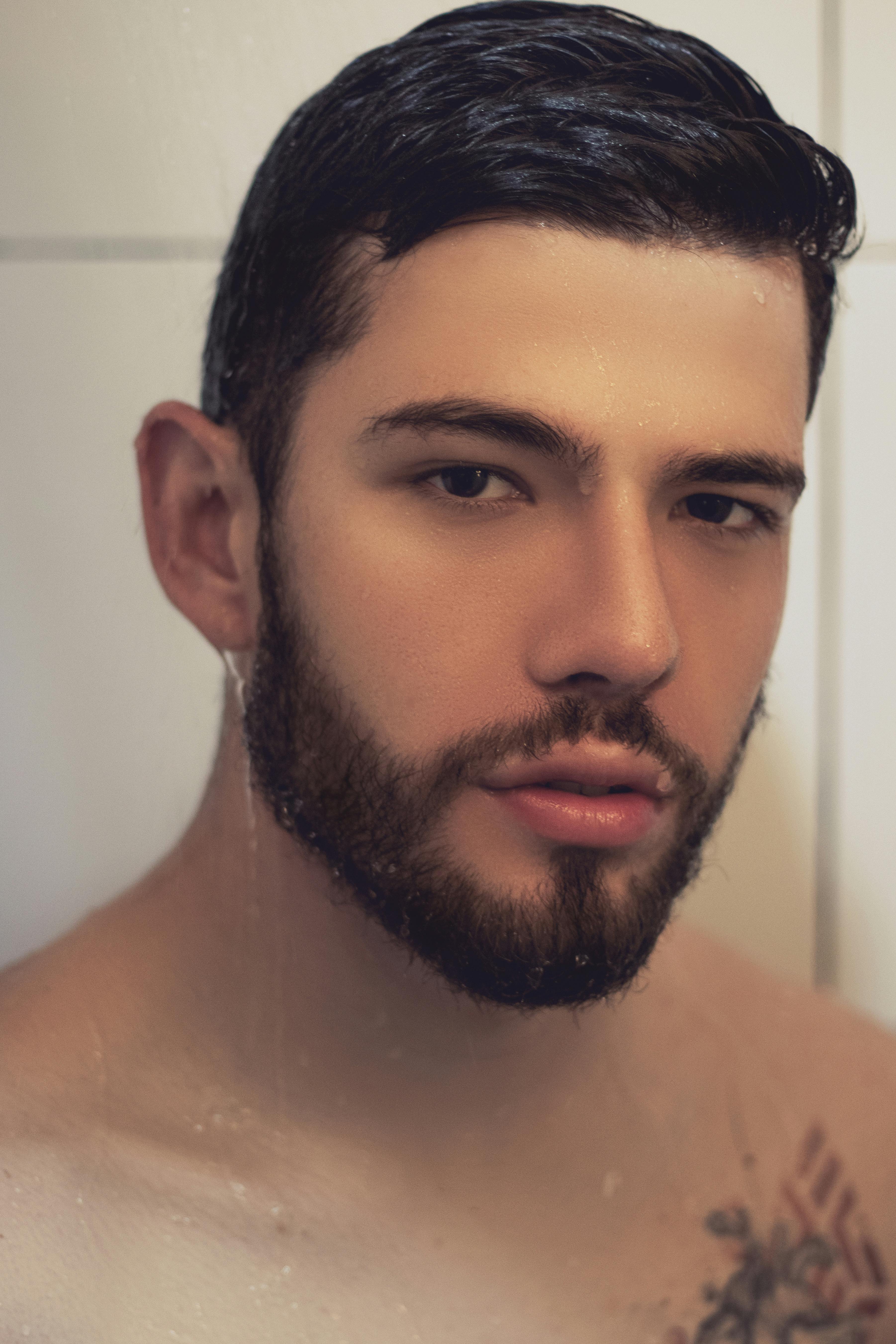 Close-up portrait of a bearded man with wet hair, looking at the camera.