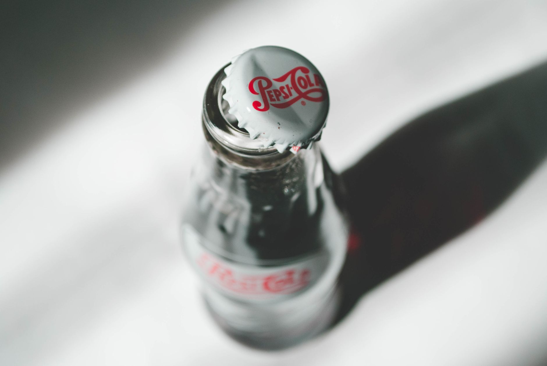 Close-up of a cola glass bottle with a shadow in soft light.
