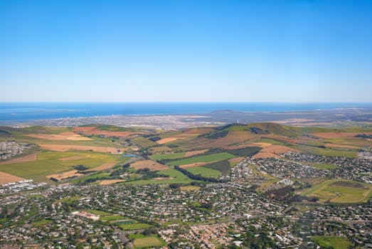Stunning aerial view of a coastal town surrounded by lush farmland and rolling hills.