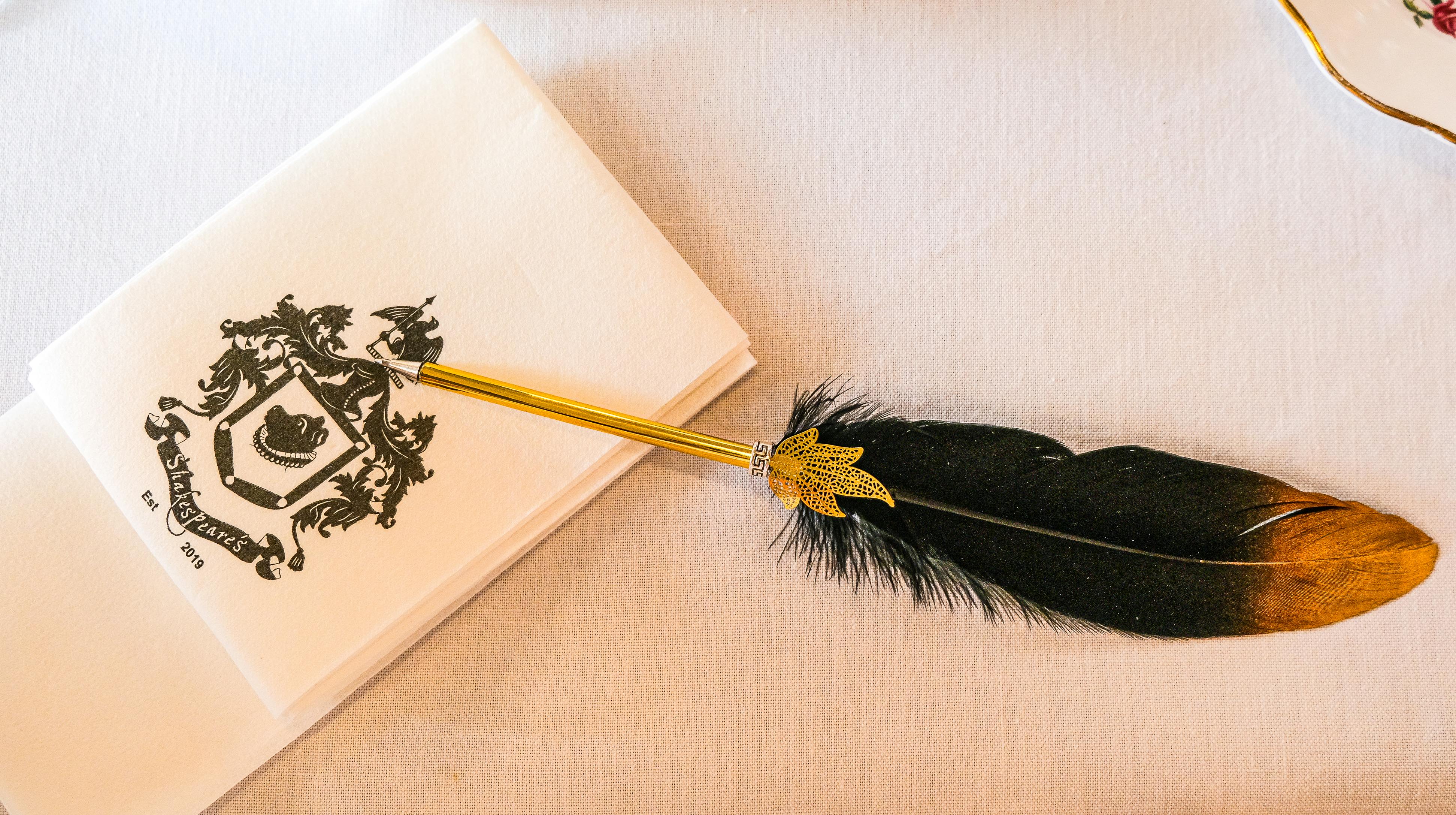 A stylish black and gold quill pen resting on a vintage napkin embossed with an elegant crest.