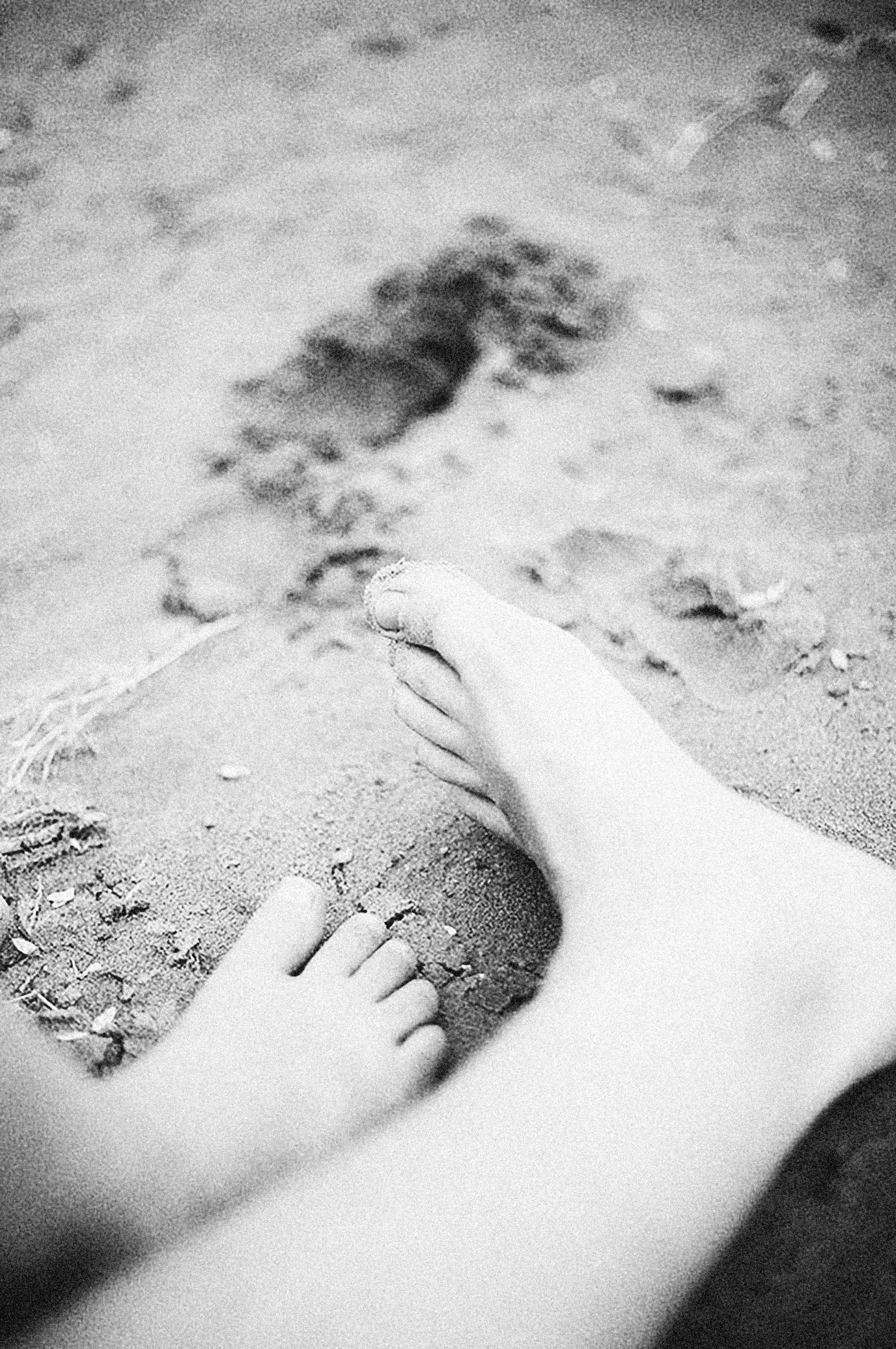 two human bare feet on sand