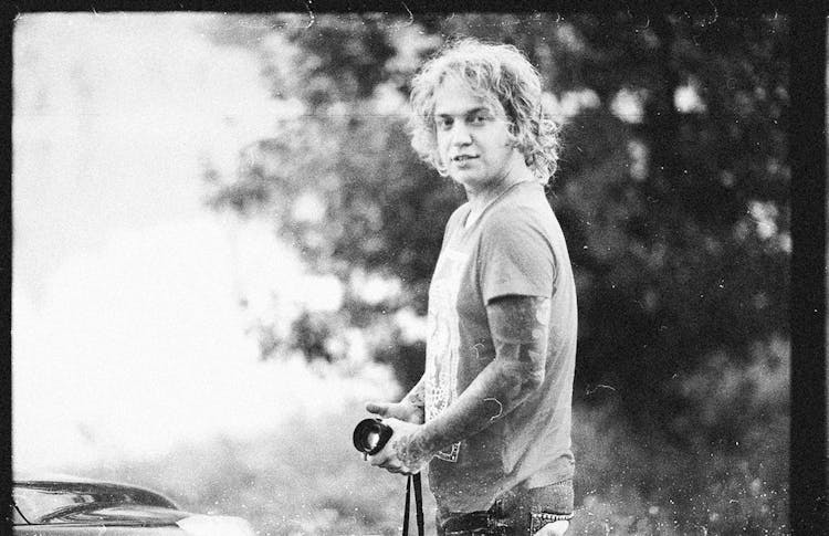 Blond Man With Tattoo On Arm Standing With Photo Camera In Hands