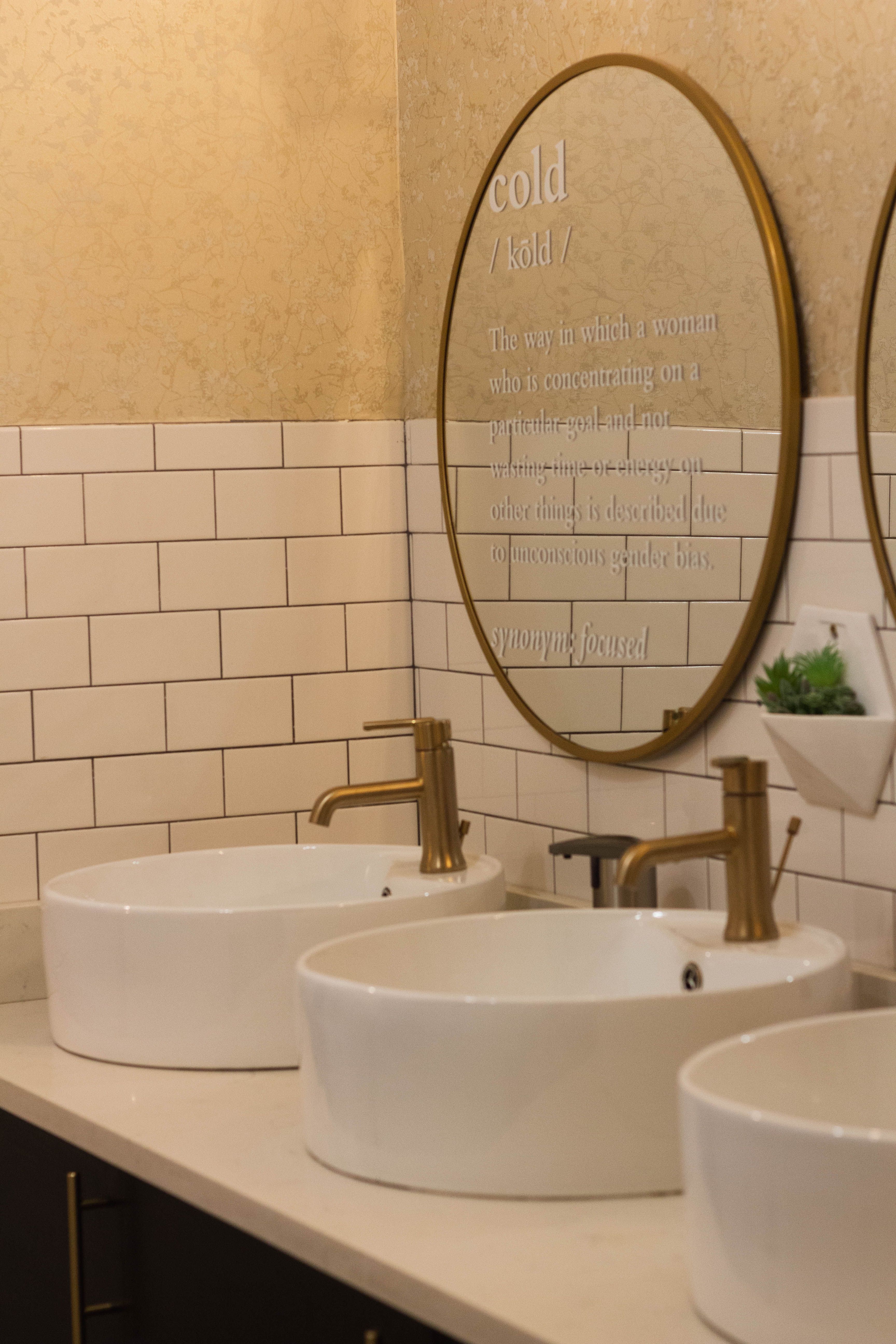 Coordinated metal faucet finishes and mirror installation at a modern bathroom vanity