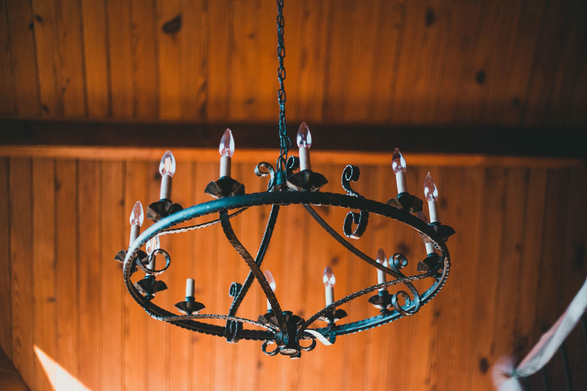 A vintage metal chandelier hanging from a warm wooden ceiling, creating an antique ambiance.