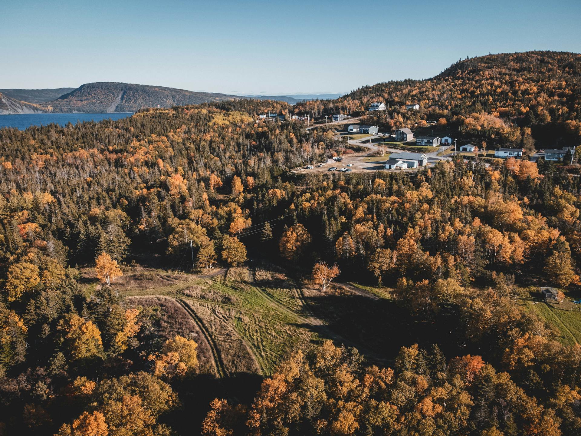 Discover the beauty of a mountain village surrounded by autumnal forests and distant hills.