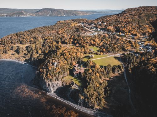 Free Breathtaking aerial view of a coastal village surrounded by autumn foliage and rugged landscape. Stock Photo